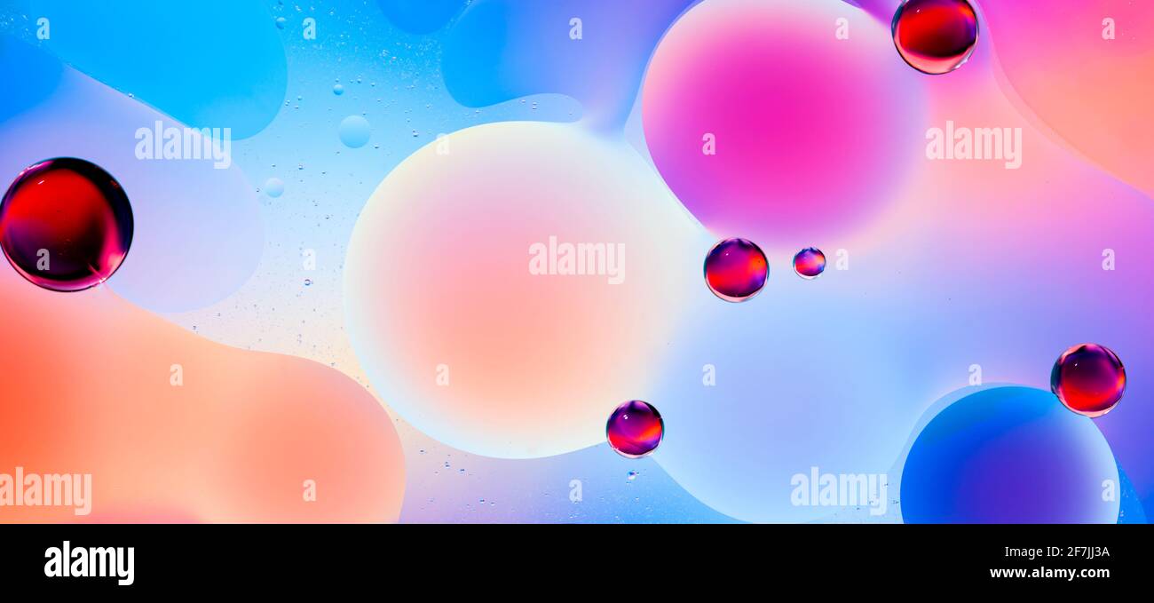 colorful oil drops on water with bright gradient background Stock Photo