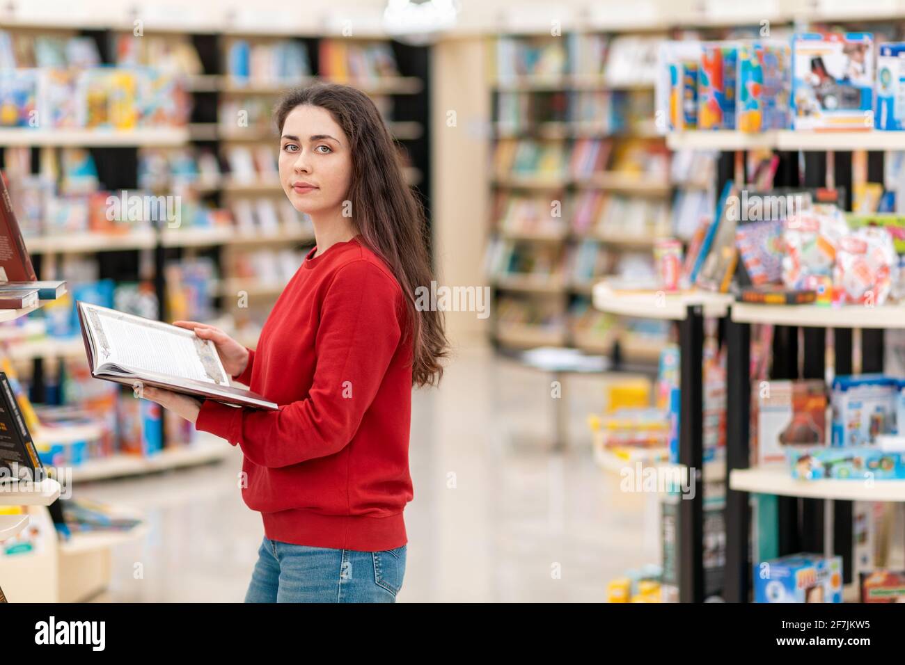 Teenage girl (16-17) posing for portrait while reading book outdoors -  Stock Photo - Dissolve