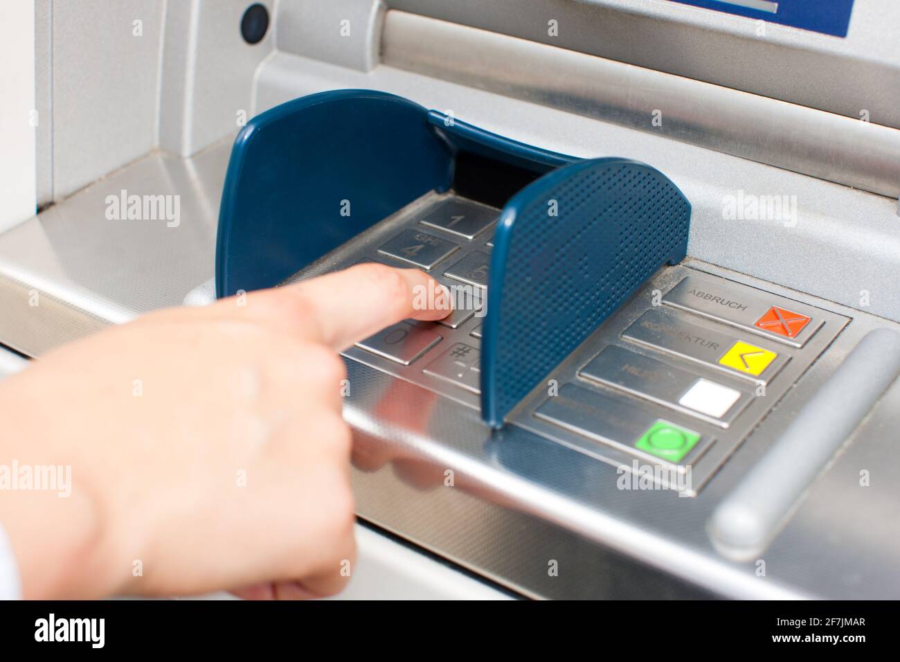 Woman at ATM or cash dispenser and is entering her PIN; only hand to be seen Stock Photo