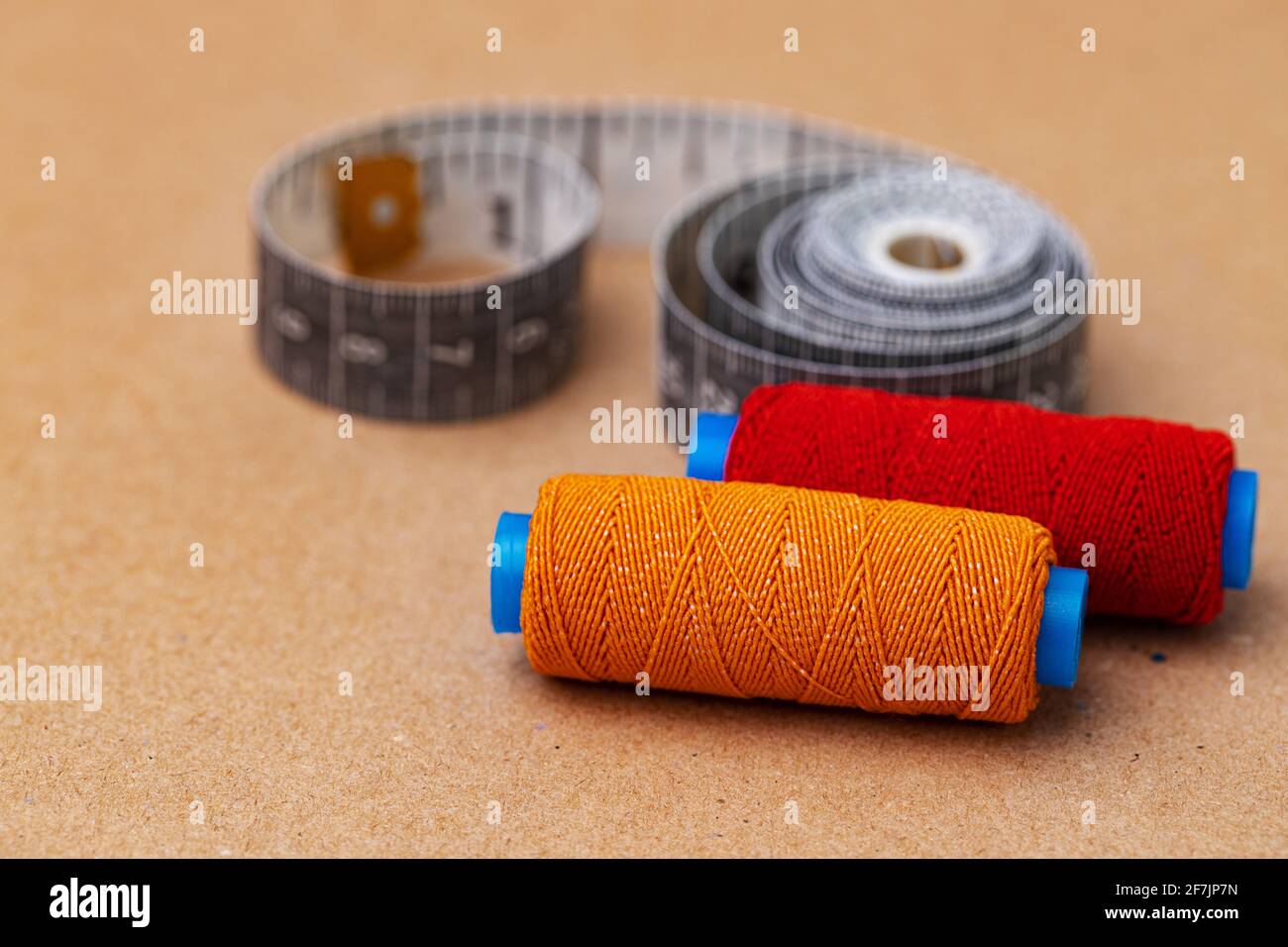 Two thread spools and measuring tape on beige background Stock Photo