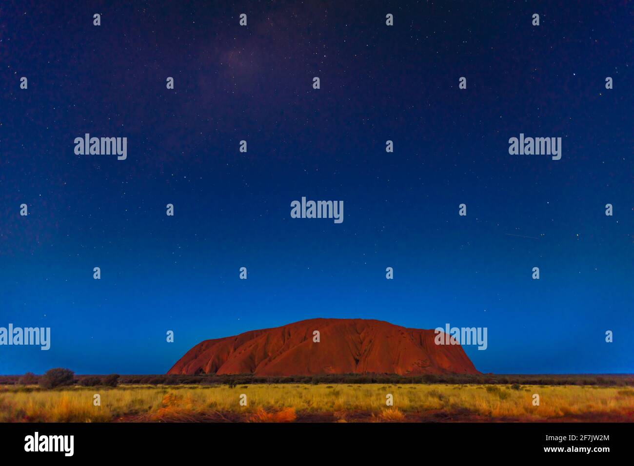 Uluru by night with bright stars in the sky. Starry sky in Uluru-Kata Tjuta National Park in Northern Territory, Central Australia. Great copy space. Stock Photo