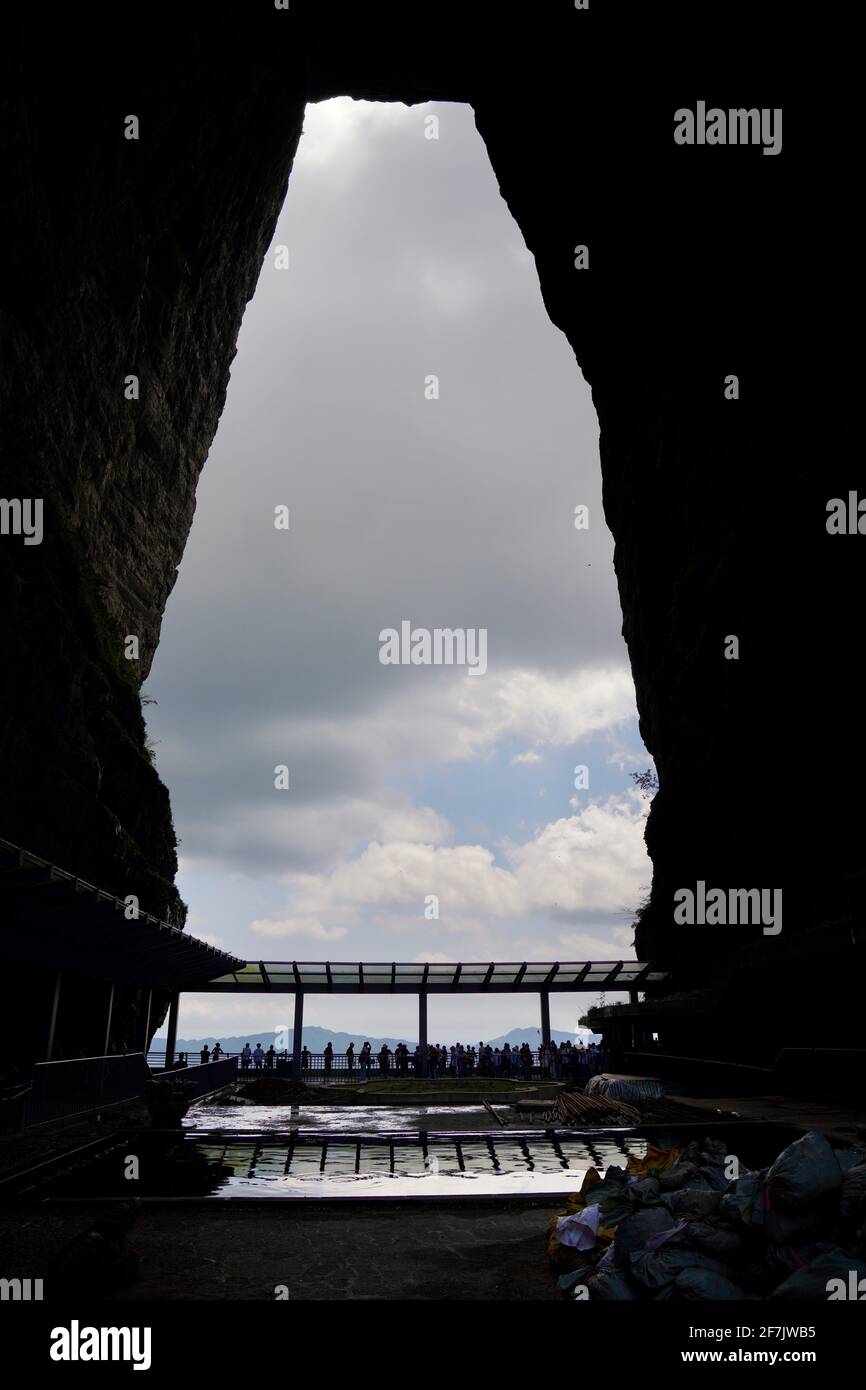 A huge hole formed by nature called TianMenDong (aka Sky Hole) in Zhangjiajie national forest park, with cloudy sky to look through. Stock Photo