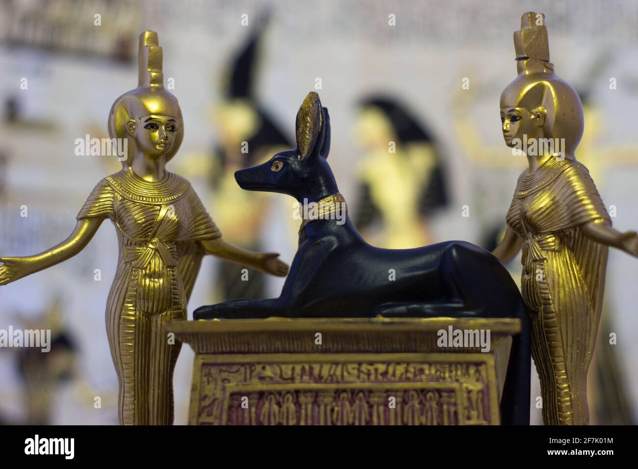 Still life with egyptian figures of anubis and the goddess nebtht and eset in gold. In the background are ancient Egyptian drawings. Stock Photo