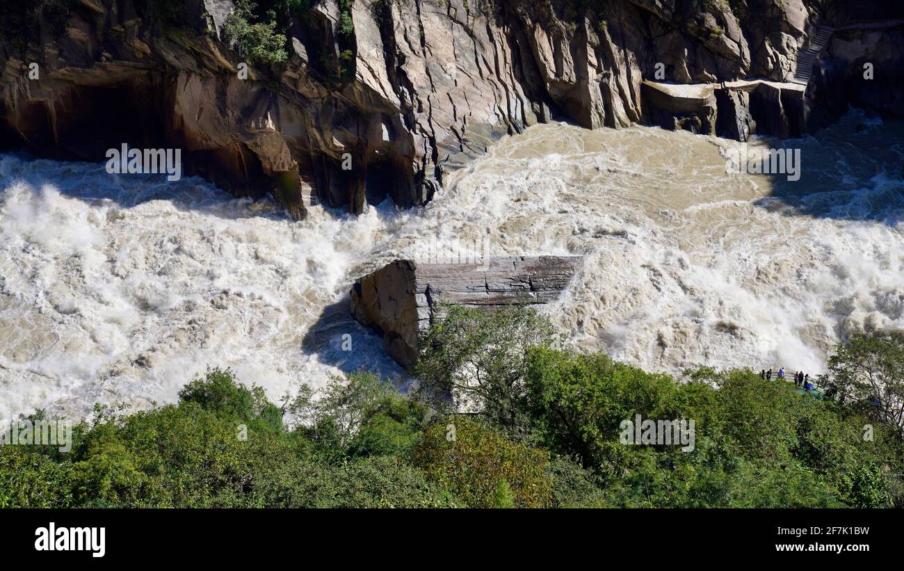 A huge stone in the middle of river with rapid water flow in Tiger Leaping Gorge of Lijiang. Stock Photo