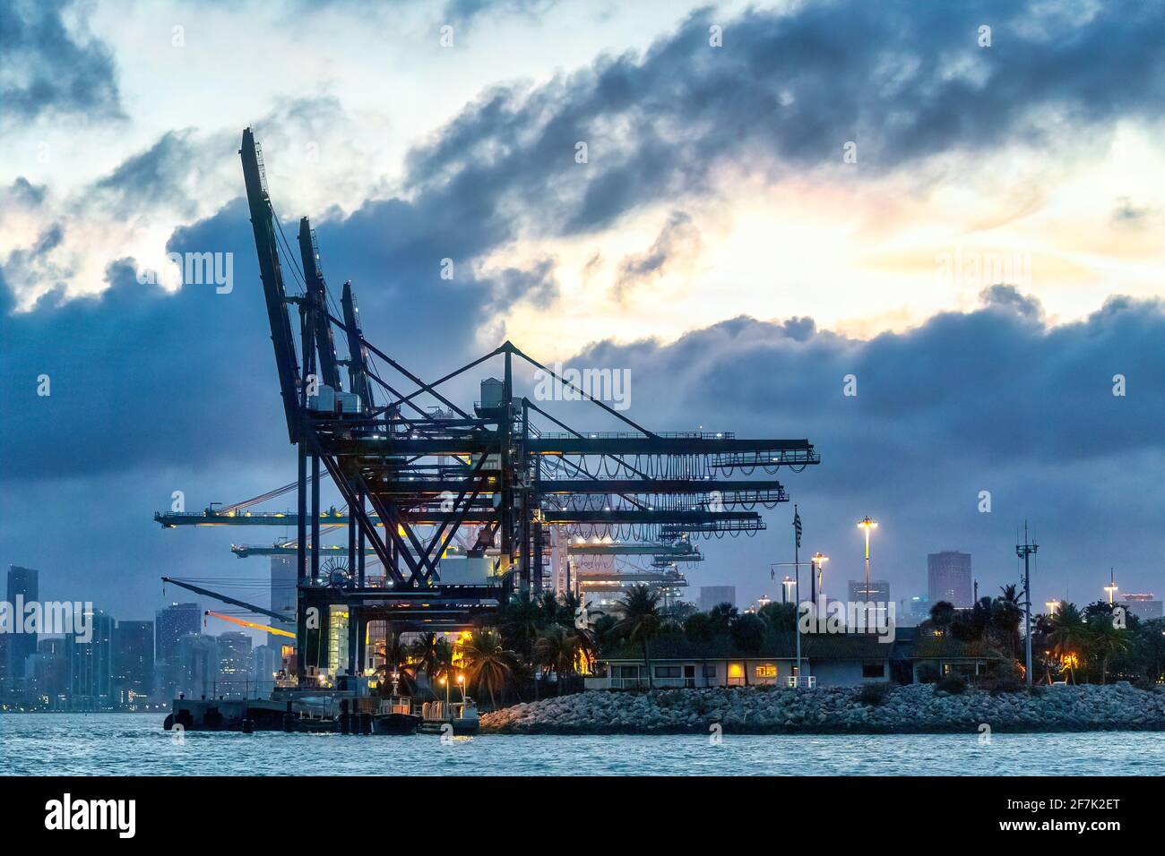 Container cranes loading cargo ships at a port during dusk under ...