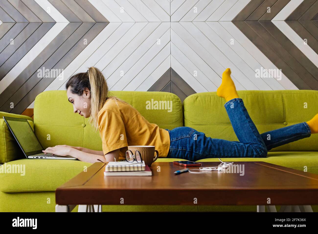 Young woman lying on the couch with her laptop Stock Photo - Alamy