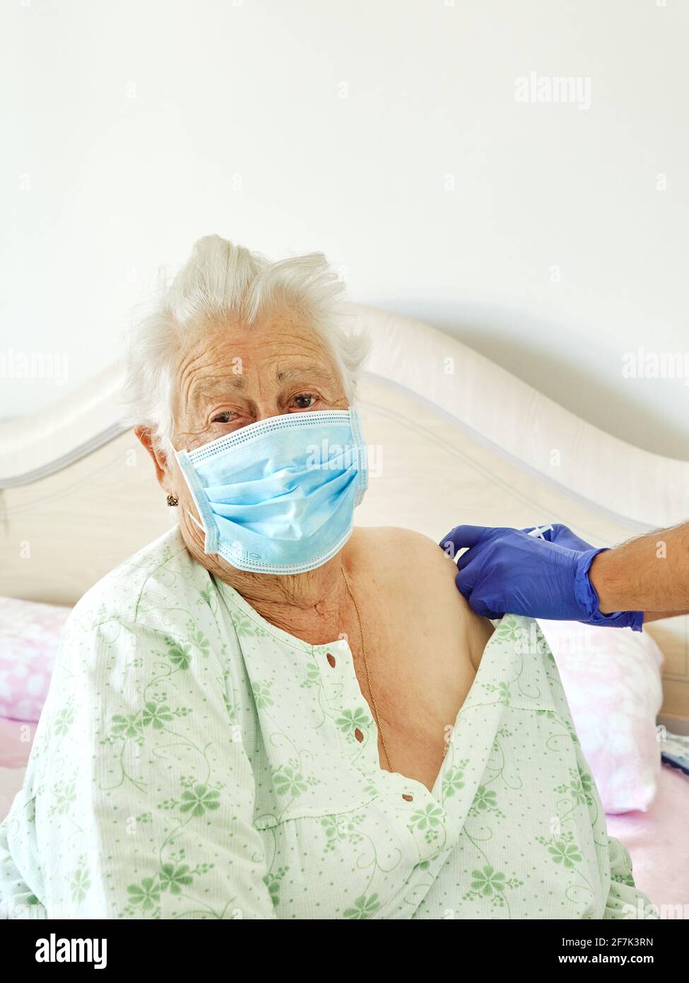 Senior adult elderly caucasian woman receives Covid-19 vaccine at home from doctor Stock Photo