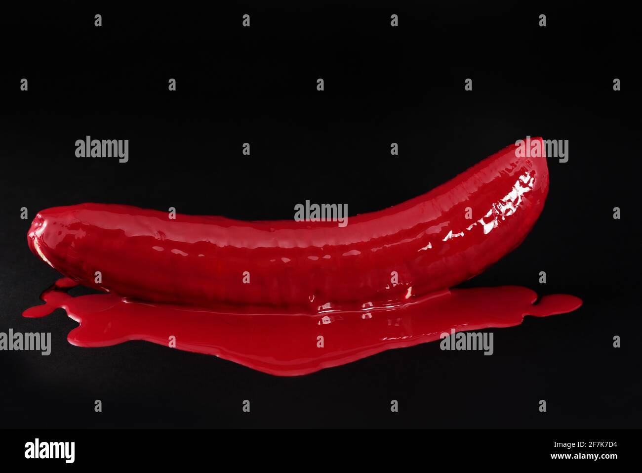 Close-up and still life of a peeled banana, which has been doused with red paint, against a dark background Stock Photo