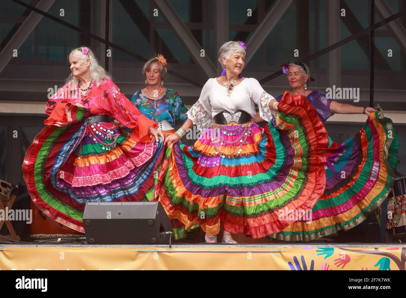 A group of gypsy dancers in long, colorful skirts performing on stage Stock Photo