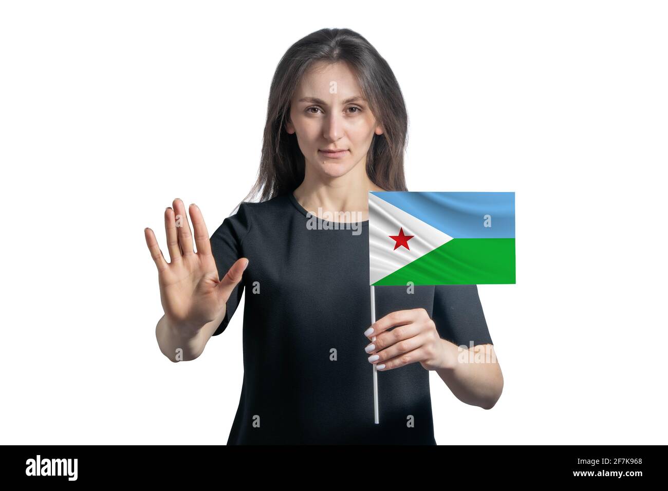 Happy young white woman holding flag of Djibouti and with a serious face shows a hand stop sign isolated on a white background. Stock Photo