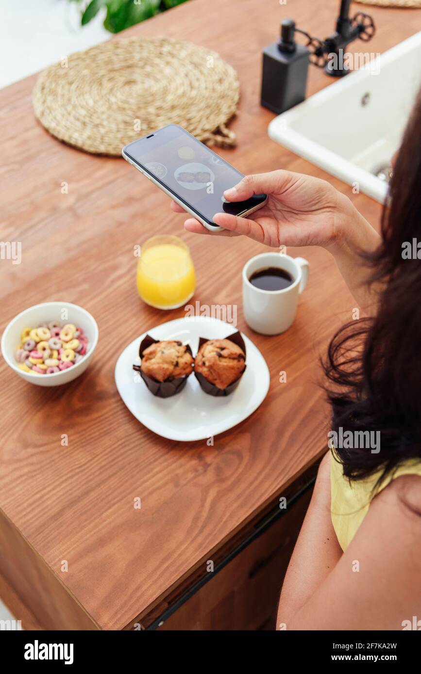 Unrecognizable woman photographing breakfast in the kitchen Stock Photo