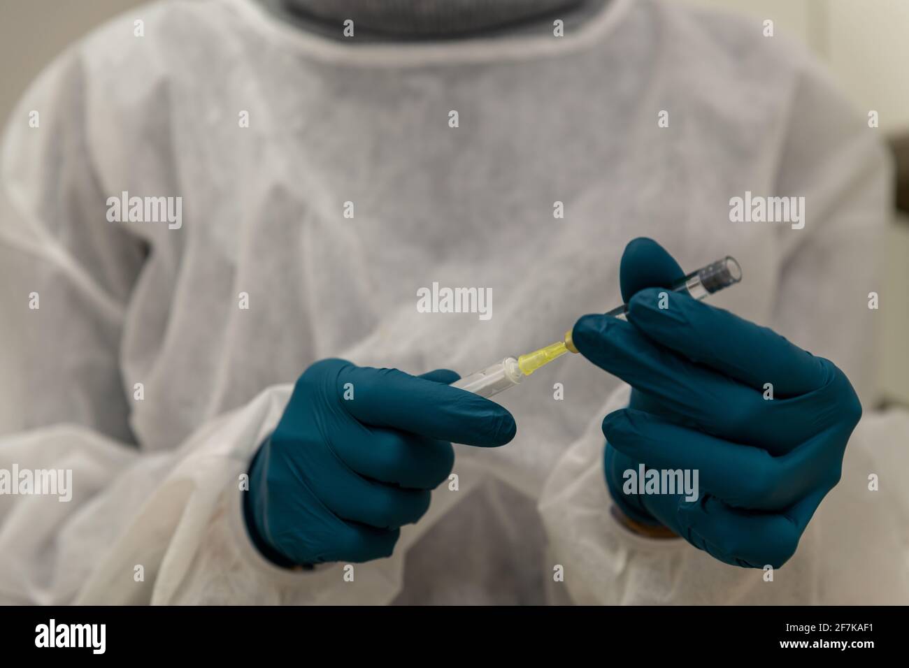 Doctor filling syringe with Corona vaccine, Covid-19, hands in rubber gloves and white coat, close up. Stock Photo
