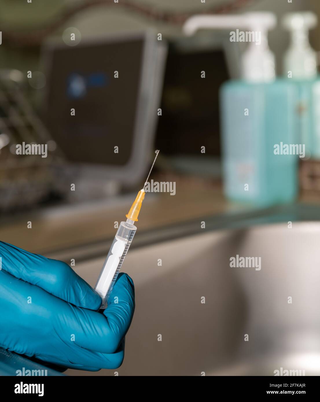 Preparation of the syringe for vaccination, doctor's hand in rubber gloves, close up. Disinfectant in the background. Stock Photo