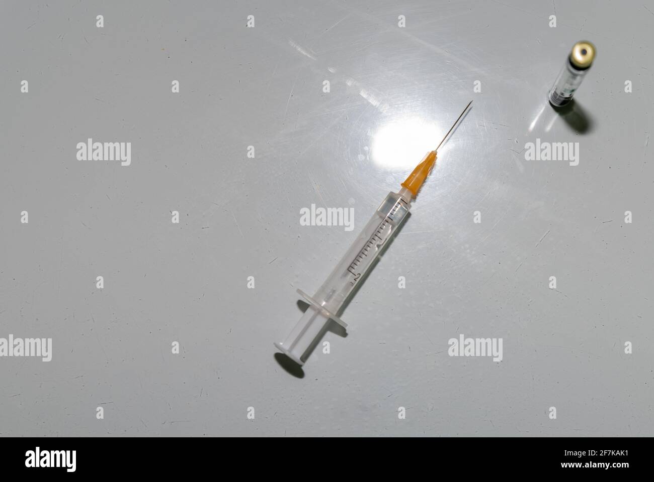 Syringe and needle with a dose of vaccine. Vaccine can against Corona, close-up on a white table. Stock Photo