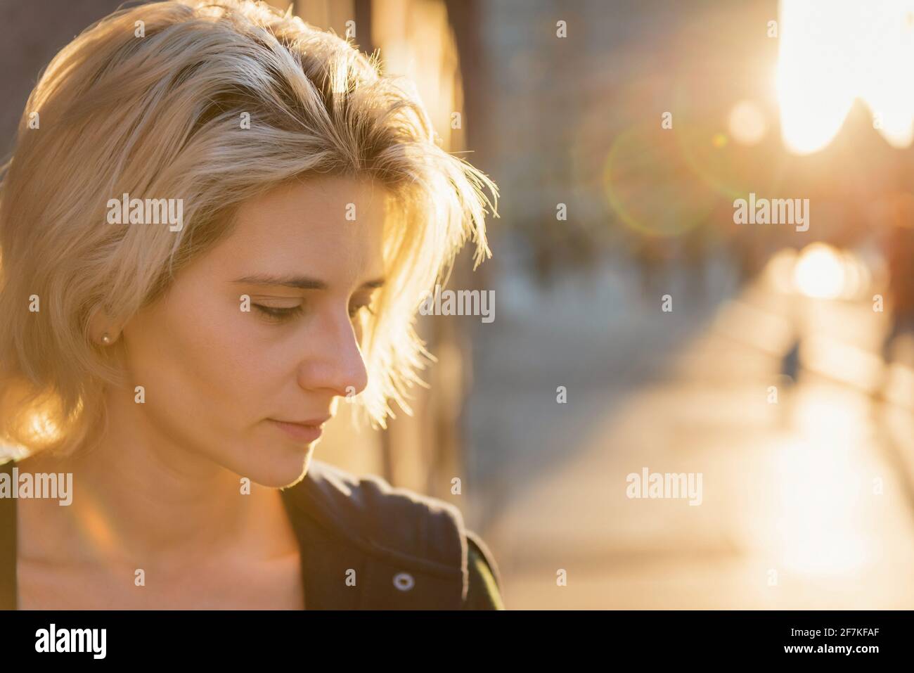 young blond woman portrait in sunset light outdoor on a city street Stock Photo