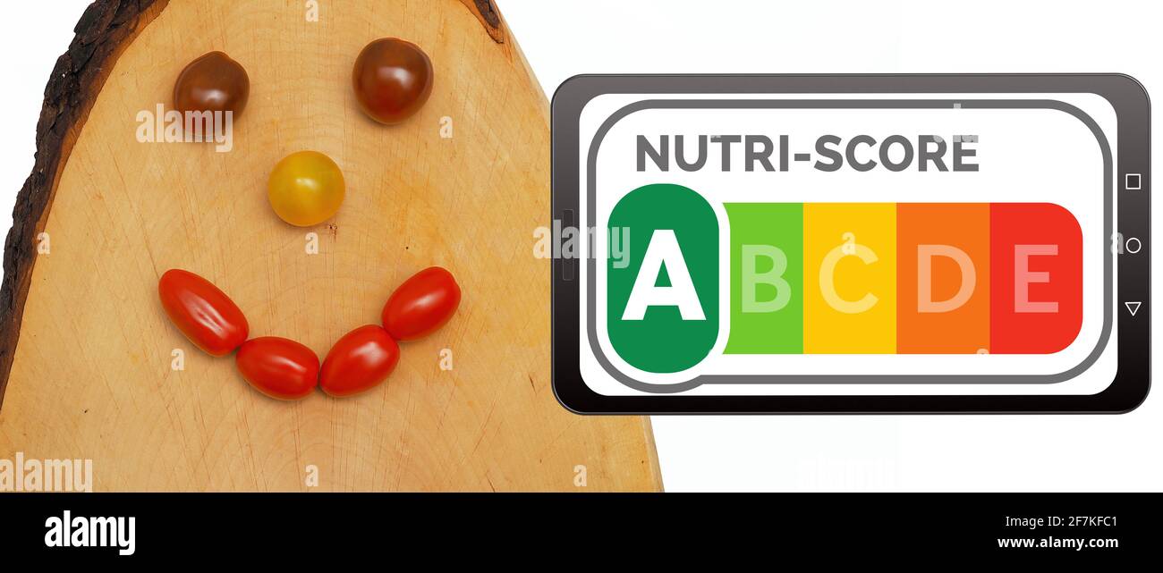Nutri-Score logo on a mobile phone display next to a laughing face made of tomatoes on a wooden board. Nutri-Score is a nutrition labelling system for Stock Photo