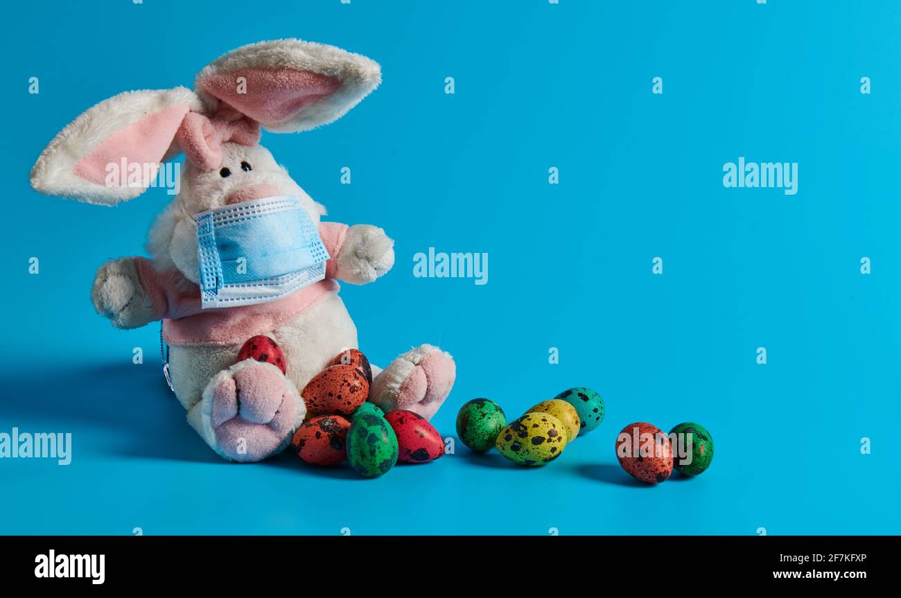 masked white hare and easter eggs lie Stock Photo