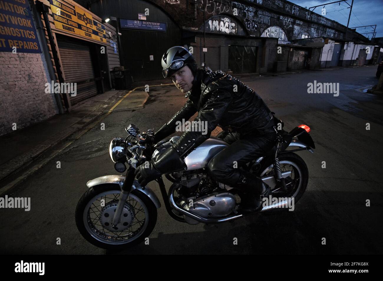 A rider races a cafe racer custom motorcycle in London , Uk Stock Photo