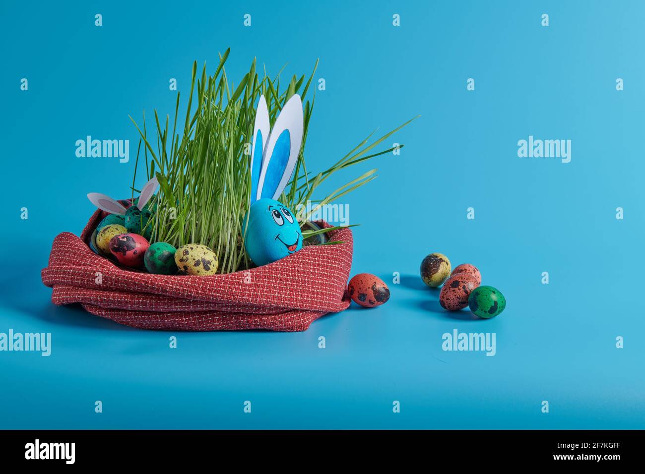 blue egg with hare ears and easter eggs in the grass Stock Photo