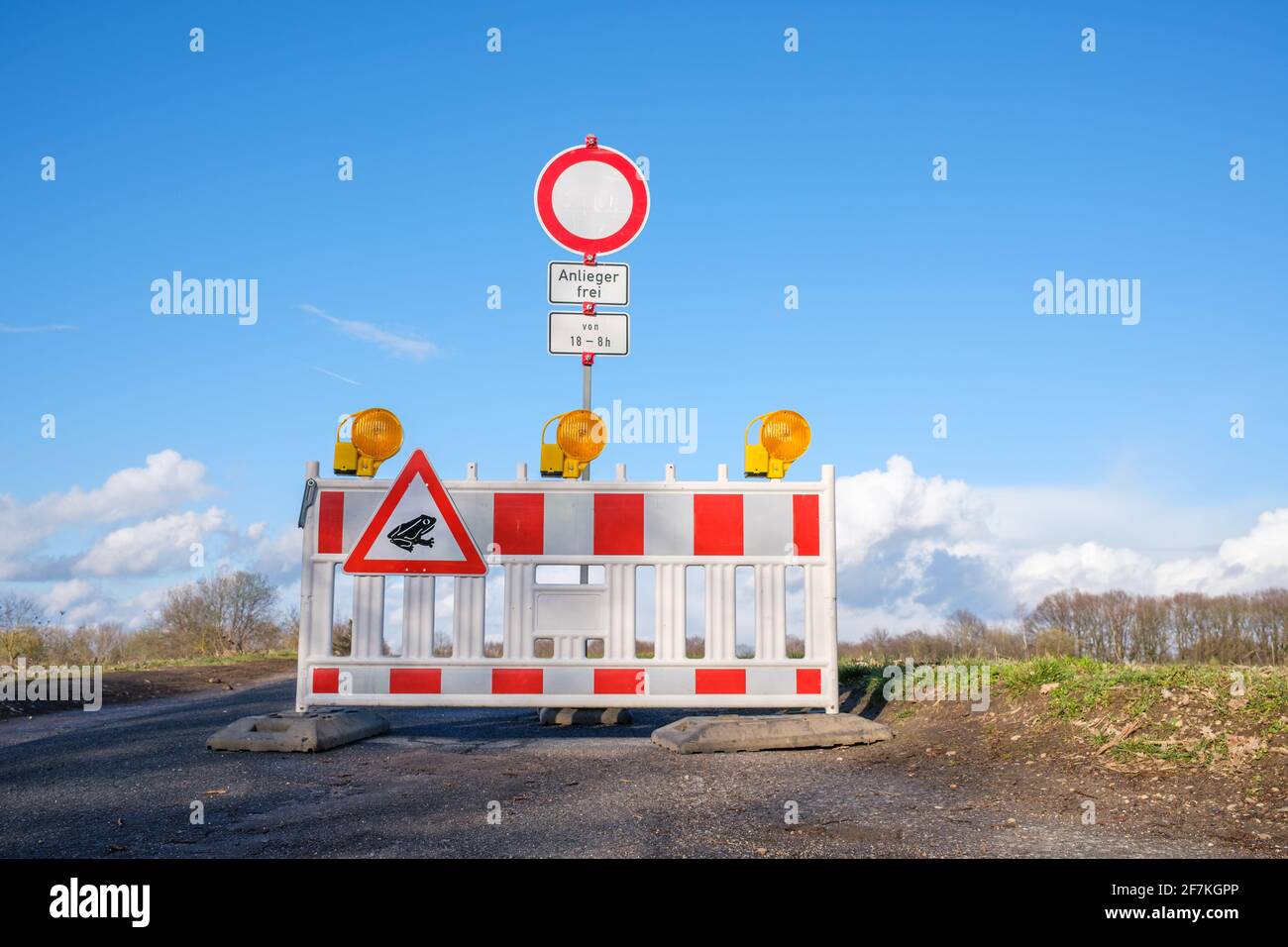 Roadblock with German traffic sign meaning 'No through traffic, residents only between 18:00 to 8:00'. Road closed with a barrier for toad migration. Stock Photo