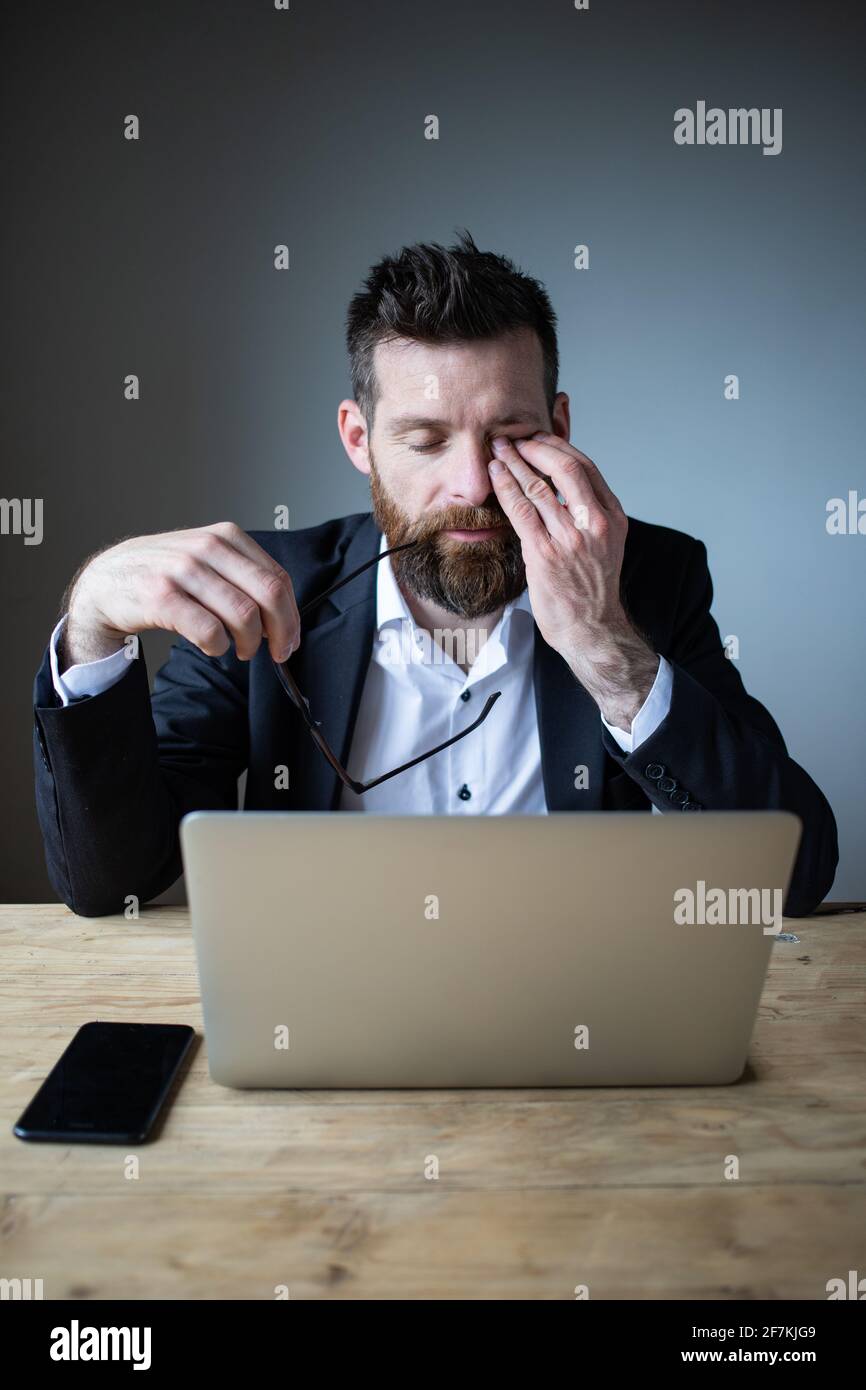 tired businessman touching his eyes bad eyesight, exhaustion Stock