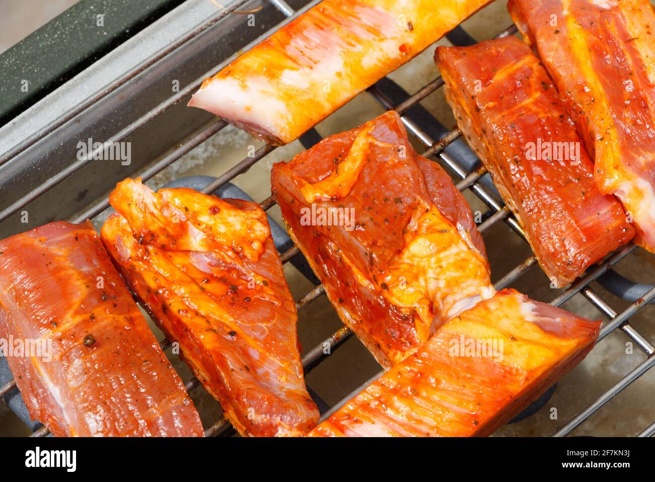 Pieces of marinated pork on the grid of an electric barbecue Stock Photo