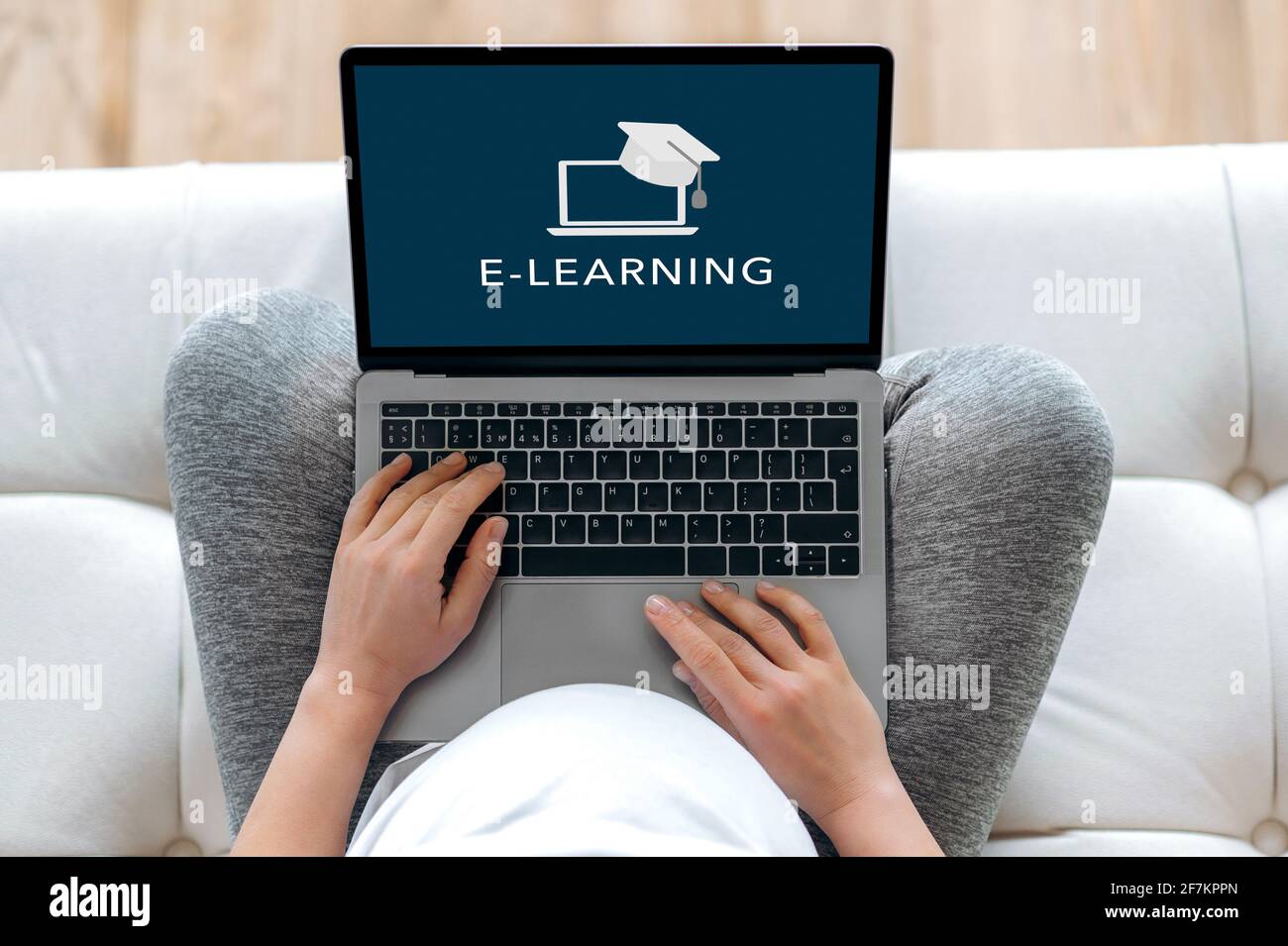 Online training during pregnancy. E-learning concept. A pregnant woman holds a laptop while sitting on the couch, learning at home during pregnancy or quarantine. Online lecture, distance education Stock Photo