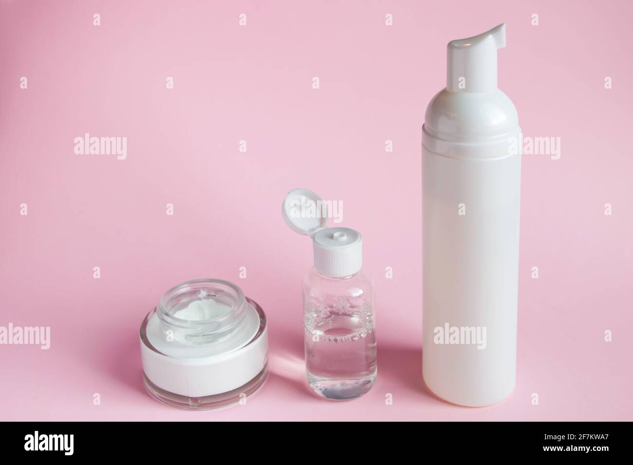 Set of cosmetics for skin care and cleansing on a pink background. The