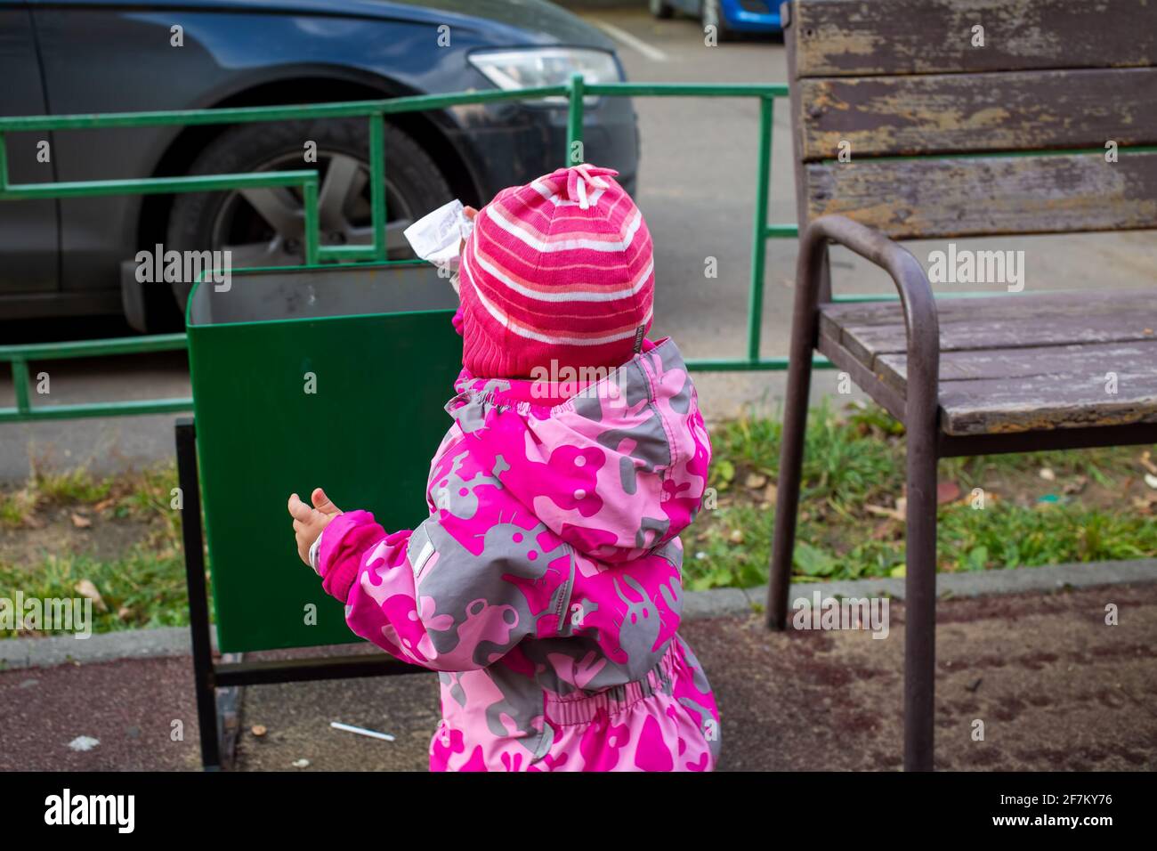 adorable toddler throws trash in a street bin Stock Photo