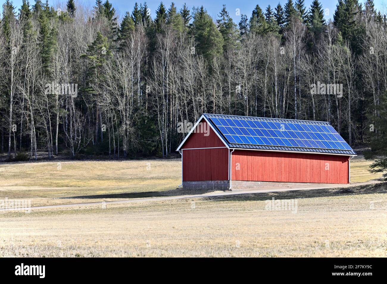 Solar panels on rooftop of a red outbuilding in rural Finland on a sunny day of spring. Stock Photo