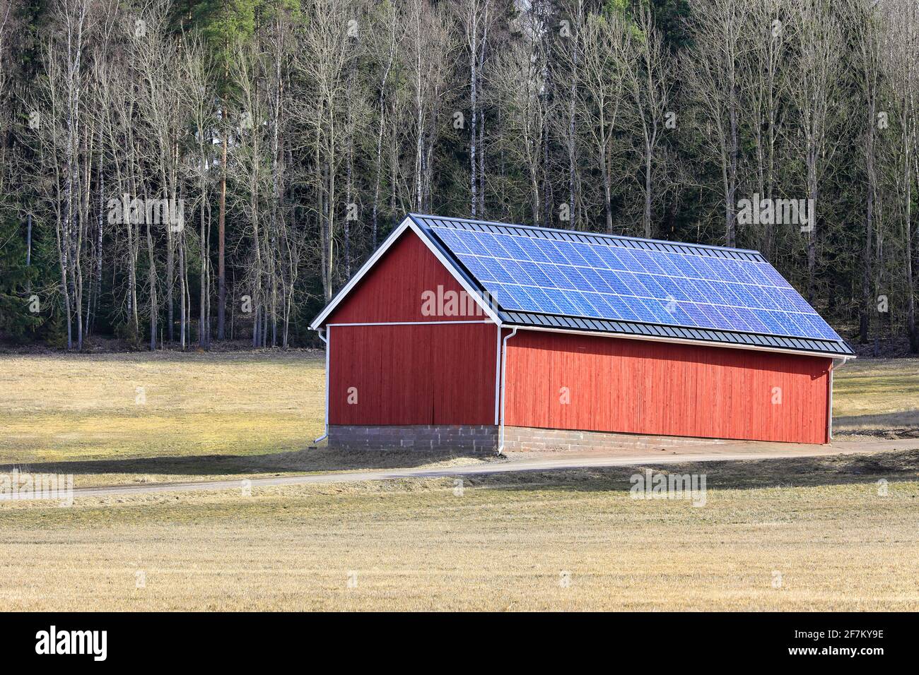 Solar panels on rooftop of a red outbuilding in rural Finland on a sunny day of spring. Stock Photo