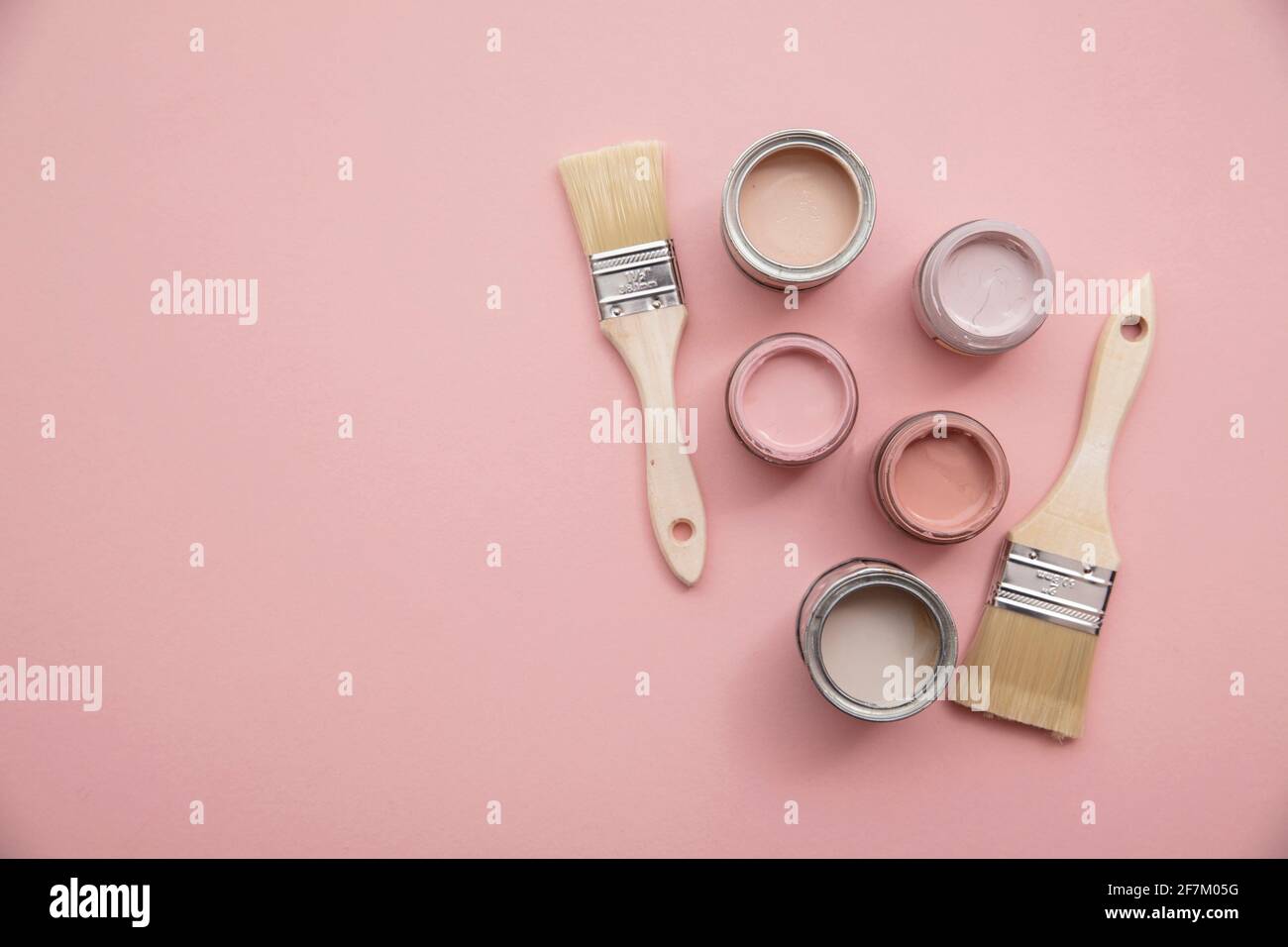 Overhead view of a DIY paint brush with pastel pink sample paint pots