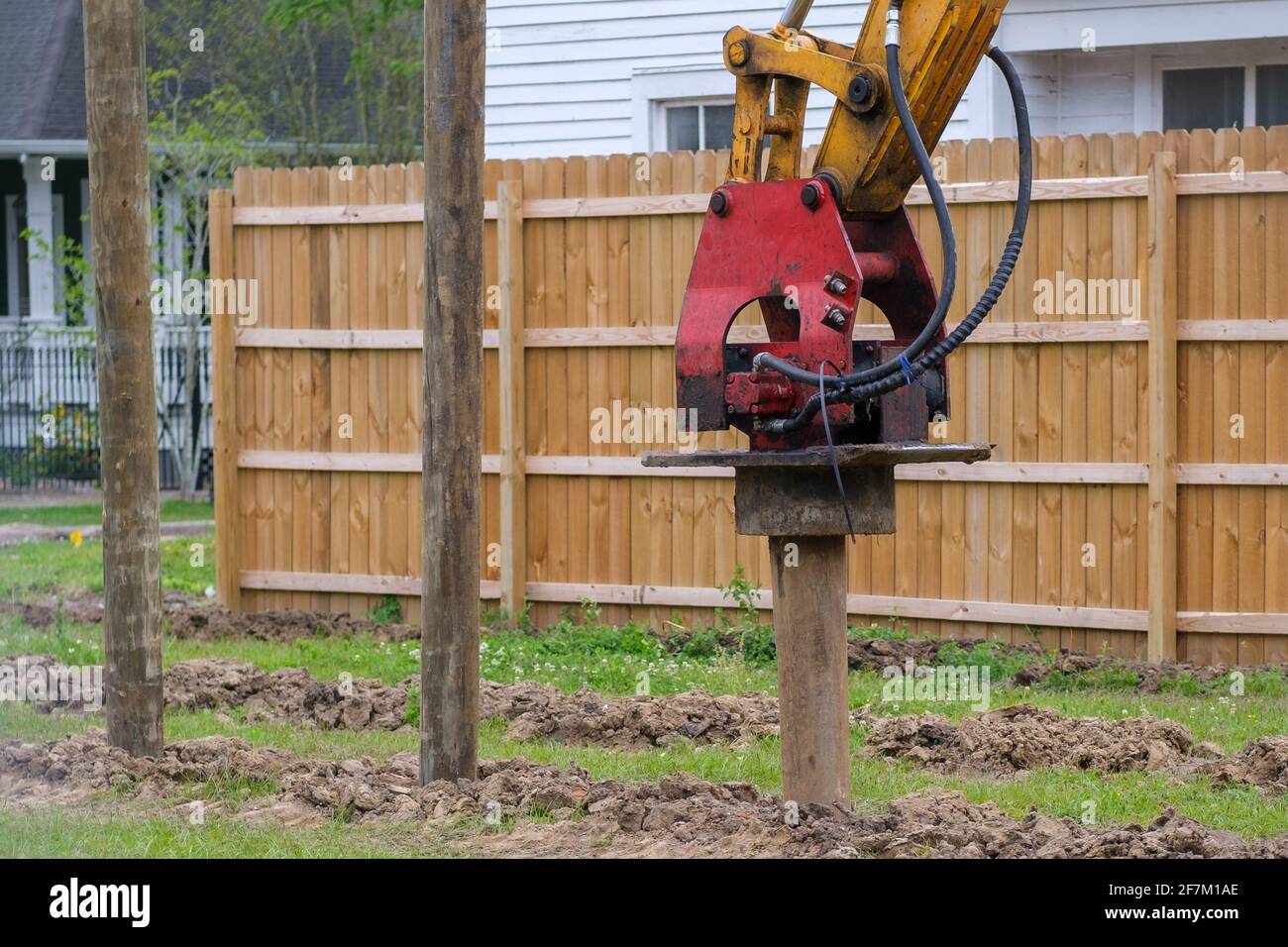Vibratory pile driver attachment in action at new residential construction site Stock Photo