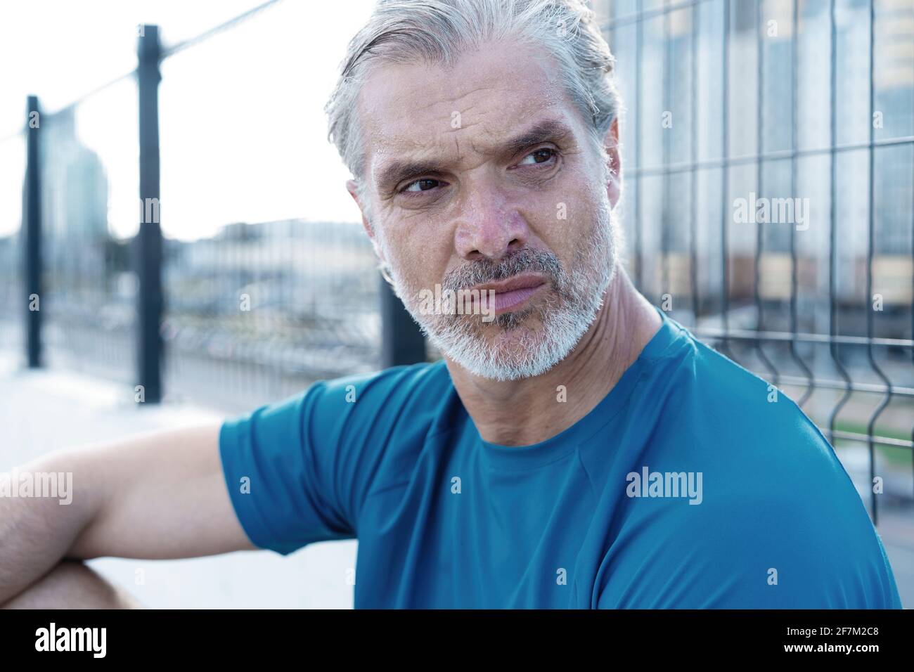 Tired Exhausted Middle-aged Man Resting After Running Outdoors. Handsome Runner Taking Break After Fitness Workout Stock Photo