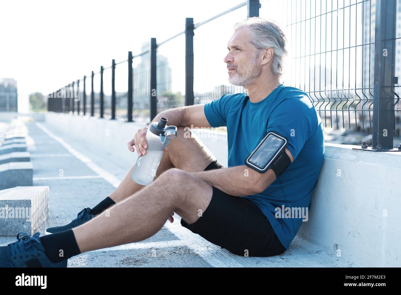 Tired Exhausted Middle-aged Man Resting After Running Outdoors. Handsome Runner Taking Break After Fitness Workout Stock Photo