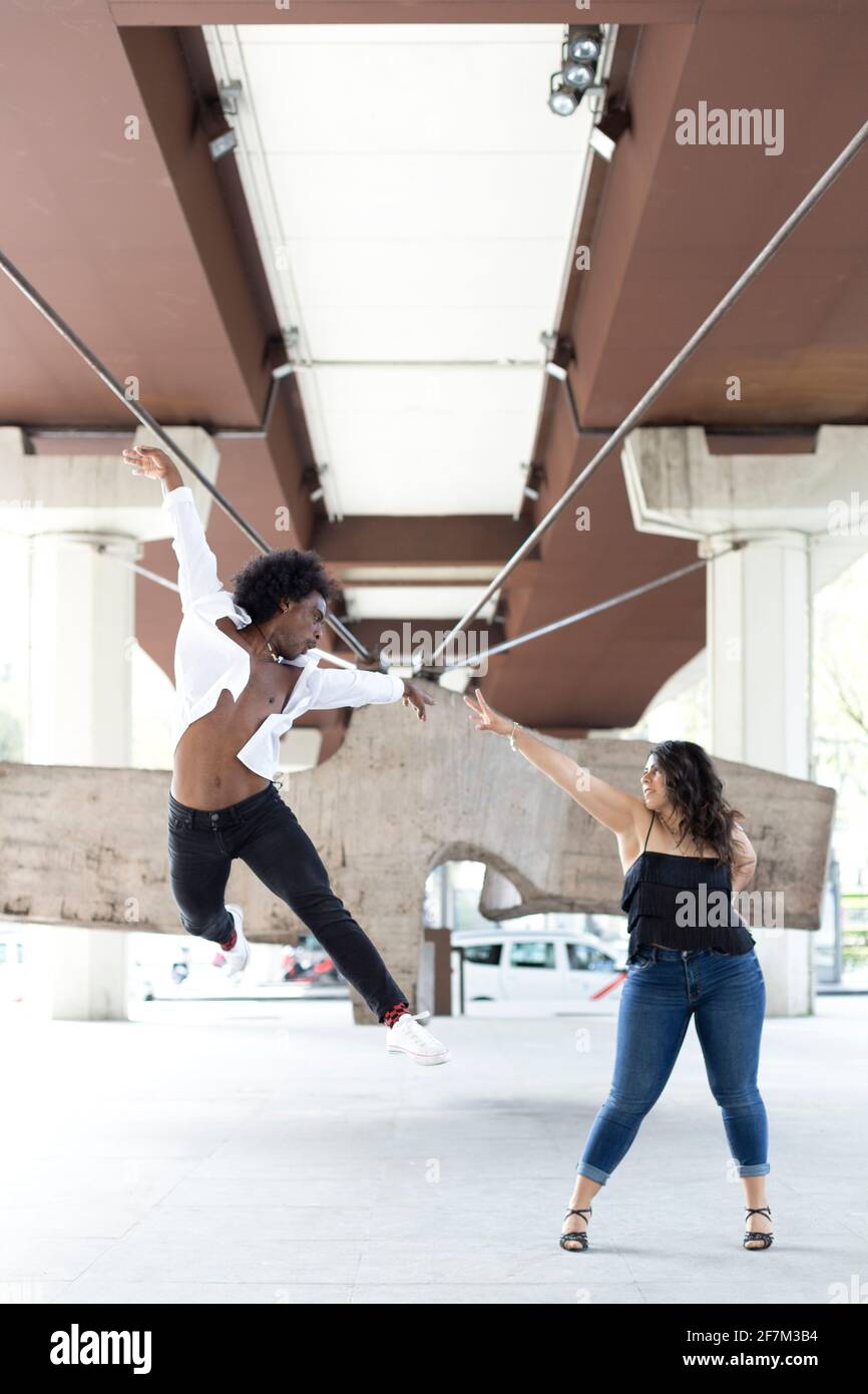 Multiracial couple of dancers doing an acrobatic jump in the city. Street dance concept. Space for text. Stock Photo