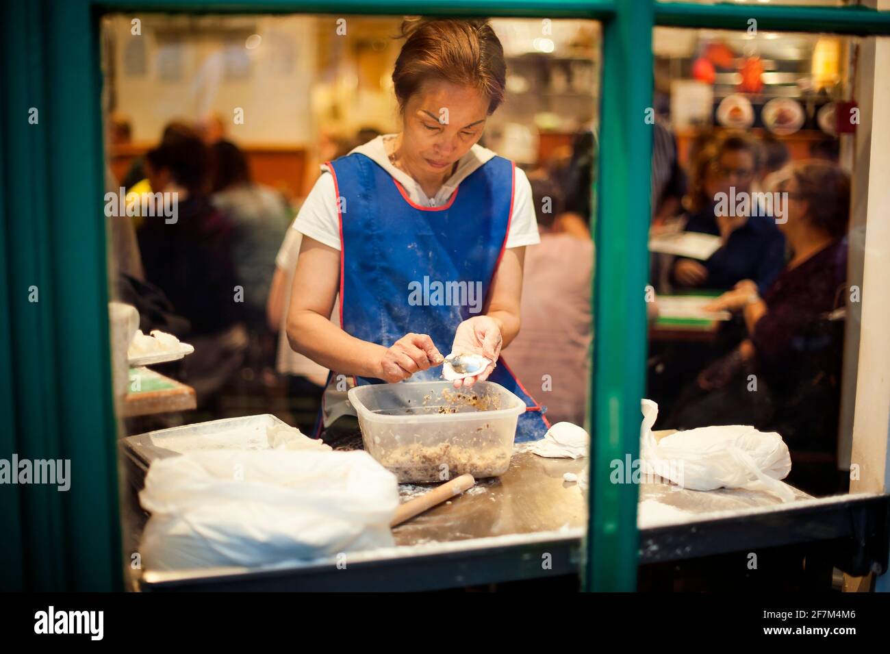 Asian woman making dumplings in Chinese (canteen style) restaurant. Chinatown, London, UK. Aug 2015 Stock Photo