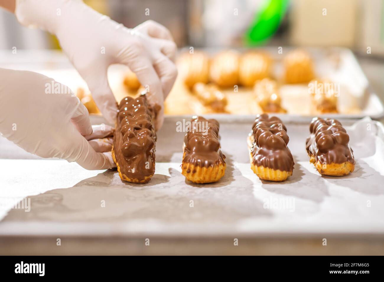 Hands carefully laying out finished eclairs on tray Stock Photo
