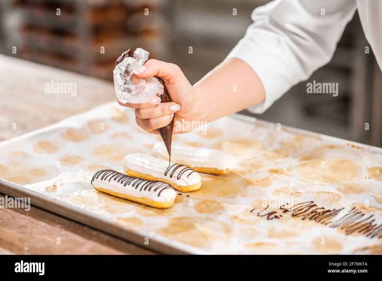 Hand decorating eclair with chocolate using pastry bag Stock Photo Alamy
