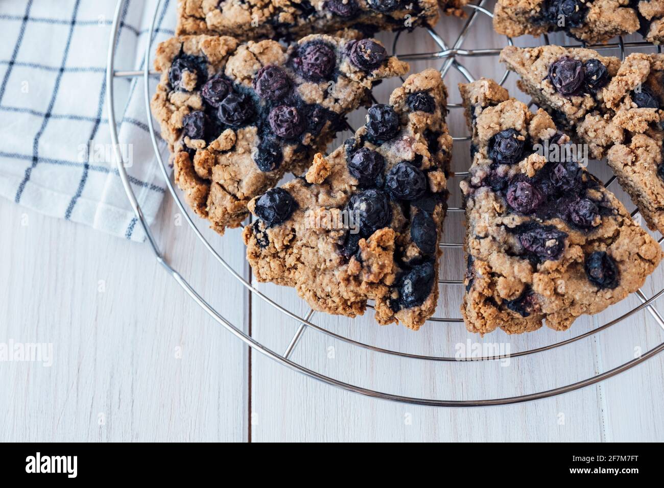 Freshly baked oat blueberry scones on cooling rack on white wooden