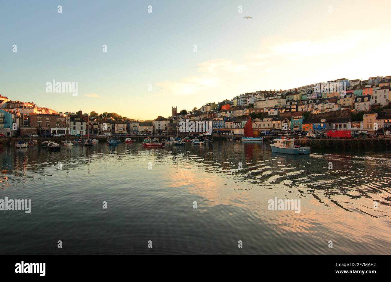 Brixham harbour catching the evening sunshine as seen in the windows of the buildings overlooking the harbour. Stock Photo