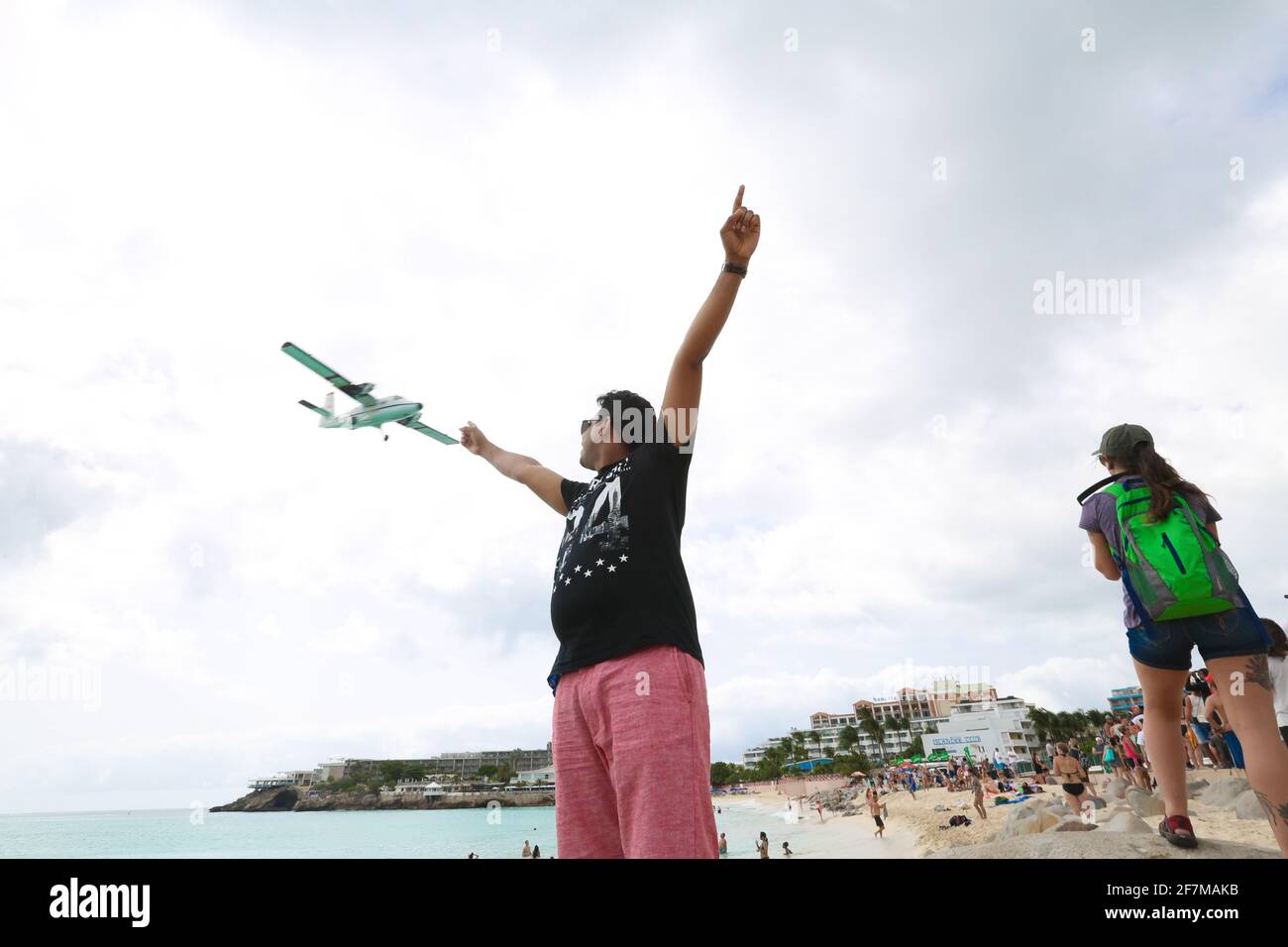 People on Maho beach are posing for pictures with airplanes that are landing on the adjacent airport. Stock Photo