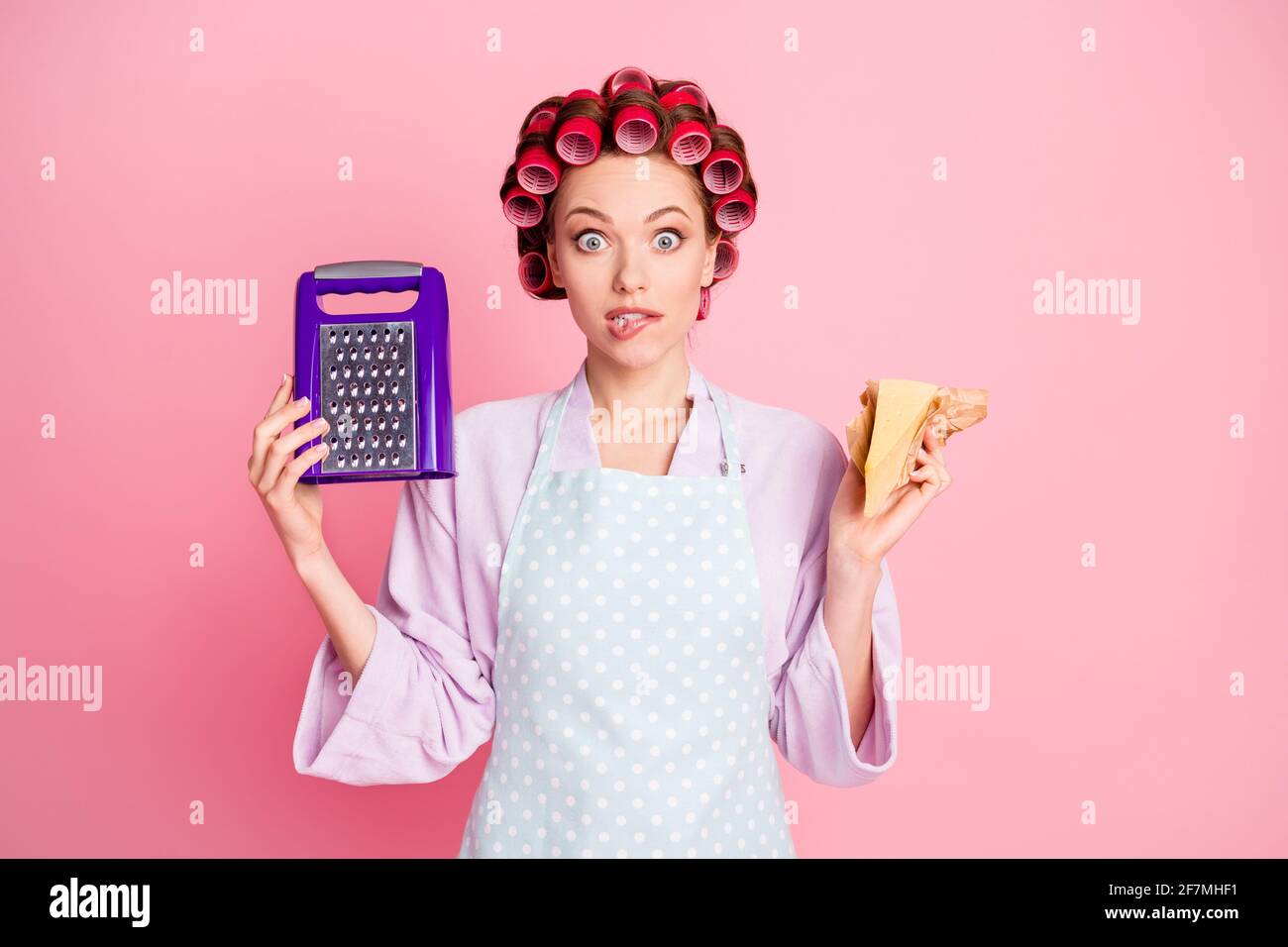 https://c8.alamy.com/comp/2F7MHF1/photo-of-scared-brown-haired-beautiful-wife-hold-cheese-grater-bite-lip-wear-dotted-apron-purple-bathrobe-isolated-on-pink-color-background-2F7MHF1.jpg