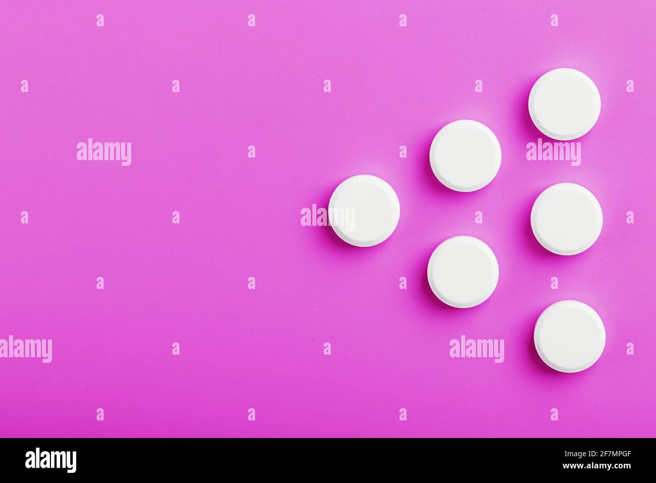 White Ecstasy pills in a row on a pink background, isolate. Top view, place for text. Stock Photo