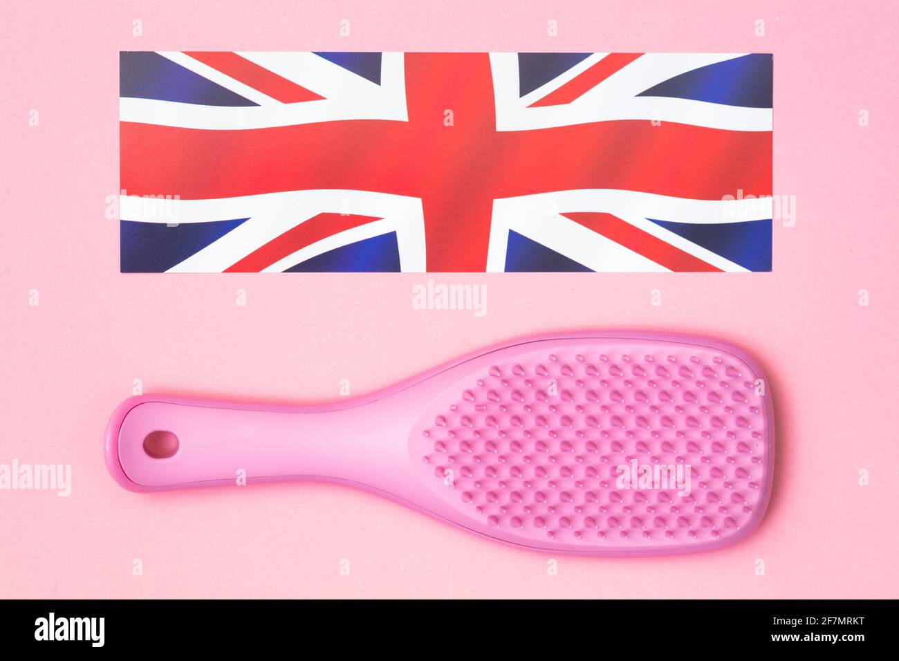 Pink hairbrush and UK flag on pink background Stock Photo
