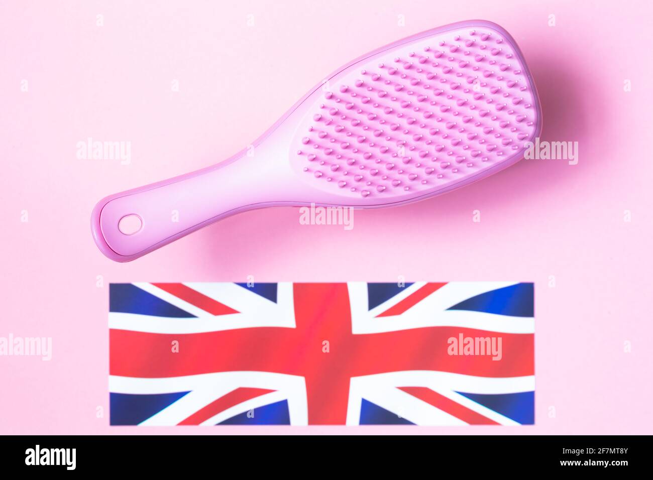 Pink hairbrush and UK flag on pink background Stock Photo