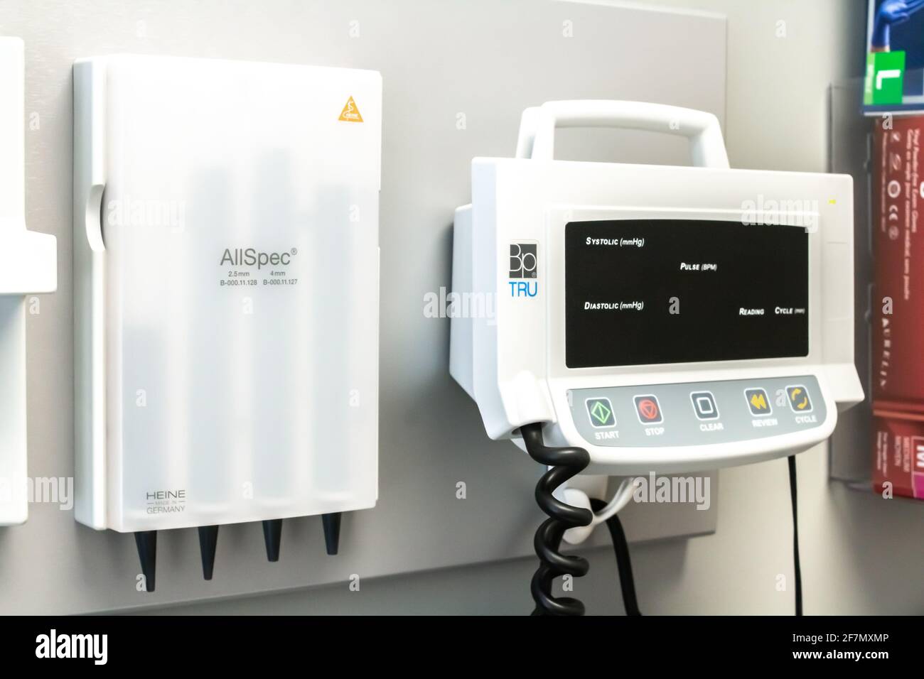 London, Ontario, Canada - February 26 2021 - Closeup of a hanging blood pressure monitor and a box of surgical gloves in a small family clinic. Stock Photo