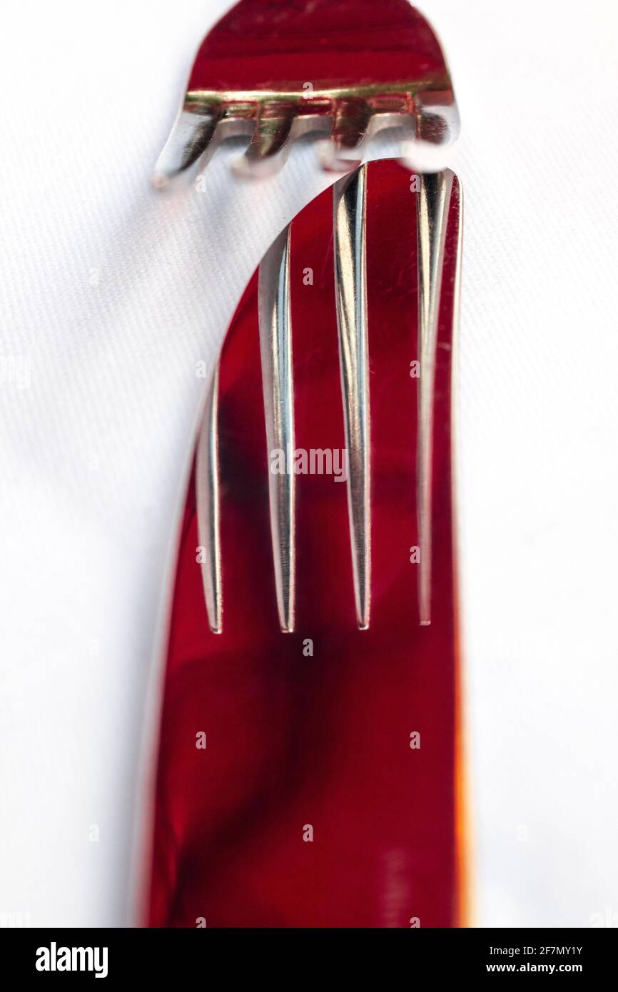Detail of red fork reflected on knife from an artistic perspective