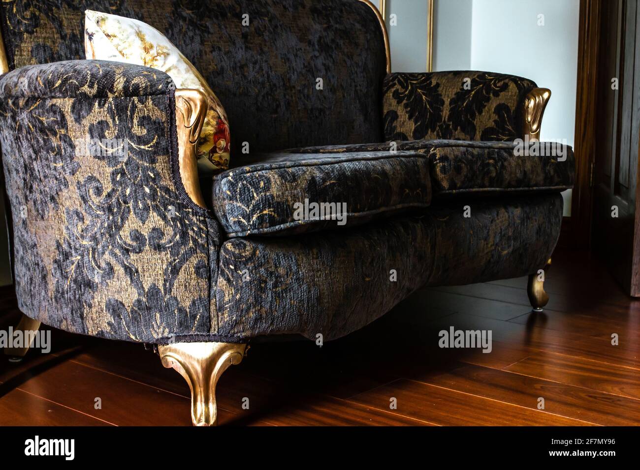 Angled photograph of a French, renaissance style lounge love seat with black lace pattern and gold legs in Ontario, Canada, February 2021. Stock Photo