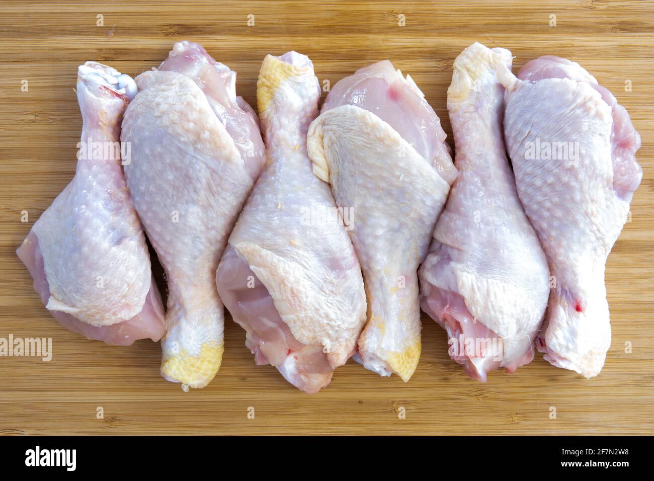 Fresh raw chicken drumstick legs on kitchen cutting board Stock Photo